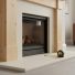 Woodworking materials and a tape measure near a modern fireplace, highlighting a non-combustible hearth designed for safe clearance.
