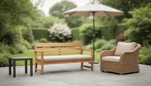 Outdoor patio furniture set with a teak bench, aluminum side table, and wicker lounge chair with neutral cushions in soft natural daylight.
