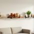 Living room wall with floating shelves made from reclaimed wood and walnut, styled with books, handmade pottery, and a small plant.